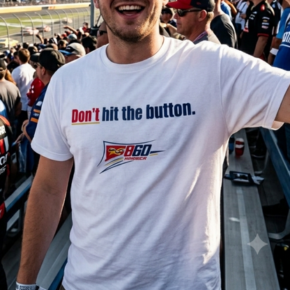 A man smiling in a race track grandstand wearing a white t-shirt with the text 'Don't hit the button.' and a Pispex 860 logo, holding up a drink.