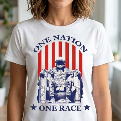A woman wearing a white graphic t-shirt with a red and blue patriotic design that reads 'ONE NATION ONE RACE' and features an illustration of a seated figure, shown in a brightly lit indoor setting.