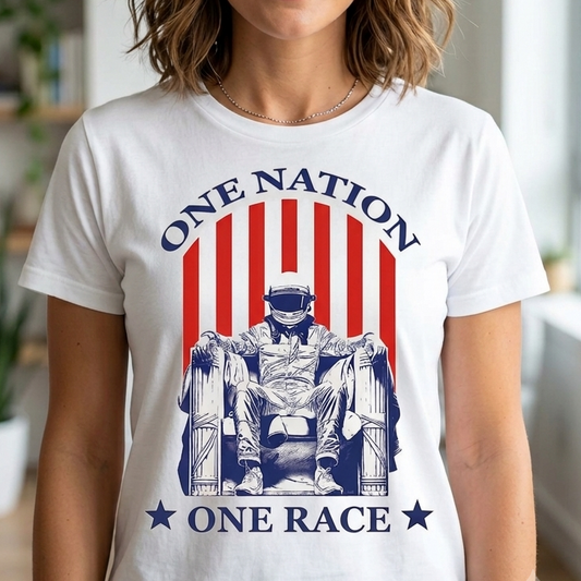 A woman wearing a white graphic t-shirt with a red and blue patriotic design that reads 'ONE NATION ONE RACE' and features an illustration of a seated figure, shown in a brightly lit indoor setting.